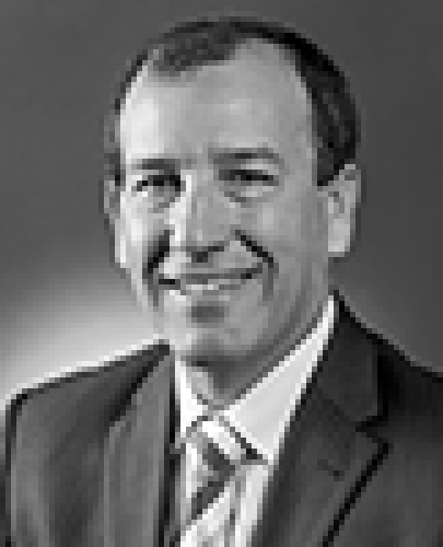 Black and white head shot of Mal Brough, former Special Minister of State. He is smiling, wearing a dark suit, shirt and tie.