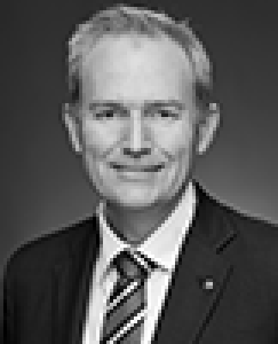 Black and white head shot of David Coleman, former Assistant Minister for Finance. He is smiling, wearing a dark suit jacket, white shirt and striped tie. 
