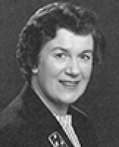 Black and white head shot of Dame Margaret Guilfoyle, former Minister for Finance. She is smiling and wearing a dark blazer, with a brooch on her lapel.