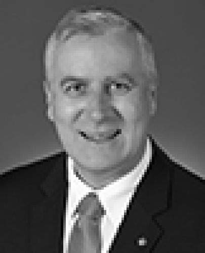 Black and white head shot of Michael McCormack, former Parliamentary Secretary to the Minister for Finance. He is smiling and wearing a dark suit jacket, white shirt and a tie.