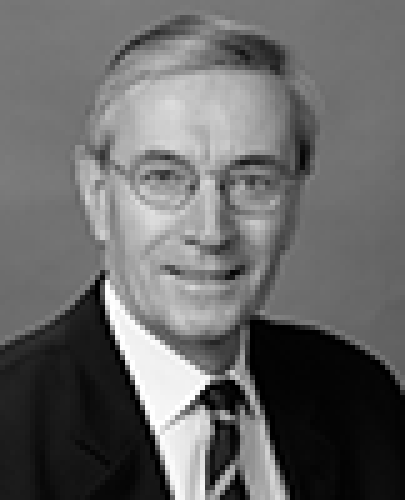 Black and white head shot of Nick Minchin, former Minister for Finance and Administration. He is smiling and wearing a dark jacket, white shirt and tie.
