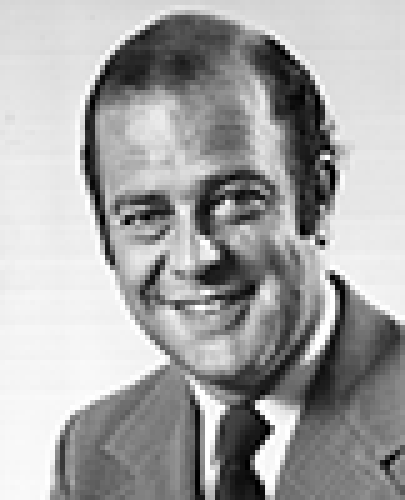 Black and white head shot of Sir Phillip Lynch, former Special Minister of State. He is smiling, wearing a light coloured jacket, white shirt and tie.