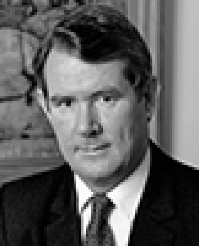 Black and white head shot of Peter Walsh, former Minister for Finance. He is smiling and wearing a dark jacket, shirt and tie. 