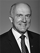 Black and white head shot of Eric Abetz, former Special Minister of State. He is wearing a dark suit jacket, white shirt and a tie. 