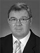 Black and white head shot of Gary Gray, former Special Minister of State. He is wearing a dark suit jacket, white shirt and a tie. 