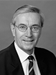 Black and white head shot of Nick Minchin, former Special Minister of State. He is smiling and wearing a dark jacket, white shirt and tie.