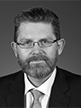 Black and white head shot of Scott Ryan, former Special Minister of State. He has a beard and is wearing glasses, a dark suit, shirt and tie.