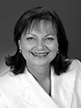 Black and white head shot of Dr Sharman Stone, former Parliamentary Secretary to the Minister for Finance and Administration. She is smiling broadly and wearing a white blazer. 